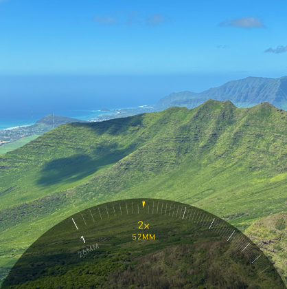 2 kat Telefoto özelliği kullanılıyor, ağaçlarla ve bitki örtüsüyle kaplı bir dağa yakınlaştırma yapılıyor