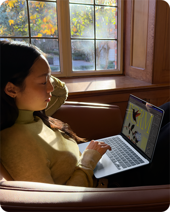 Sandalyede oturarak MacBook Air kullanan bir kişi