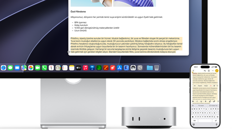 Mac mini’nin önden görünümü, Studio Display’in altına yerleştirilmiş, aygıtın ve ekranın sağ tarafında bir iPhone duruyor, iPhone’da seçili metnin üzerinde kes, kopyala, yapıştır ve AutoFill komutları görülüyor ve seçili metnin aynısı ekranda da gösteriliyor, Evrensel Pano özelliği vurgulanıyor