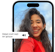 VoiceOver özelliğinin bir fotoğrafı “Dalgalı, siyah saçlı insan gülüyor.” olarak tarif ettiği iPhone 15 görseli