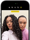 iPhone 18 Pro, siyah, önden dış görünüm, ekranında kameraya poz veren iki model var, Center Stage ön kamera gösteriliyor