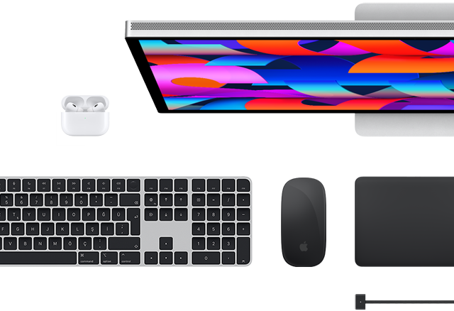Mac aksesuarlarının üstten görünümü: Studio Display, Magic Keyboard, Magic Mouse, Magic Trackpad, AirPods ve MagSafe şarj kablosu
